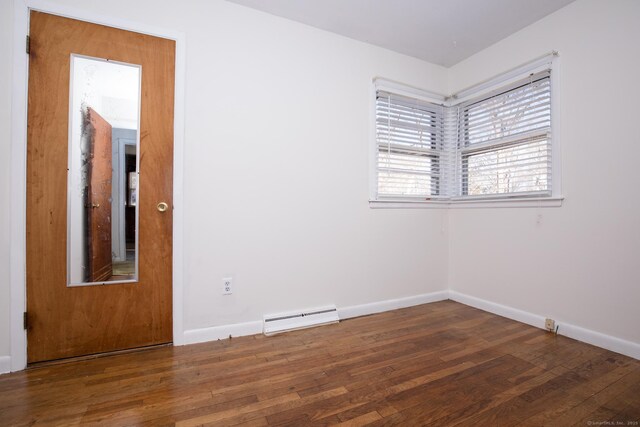 empty room with a baseboard heating unit, baseboards, and hardwood / wood-style flooring