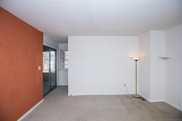 unfurnished room featuring light carpet, a textured ceiling, and baseboards