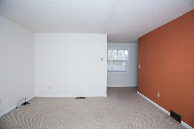 unfurnished room with baseboards, visible vents, carpet floors, and a textured ceiling