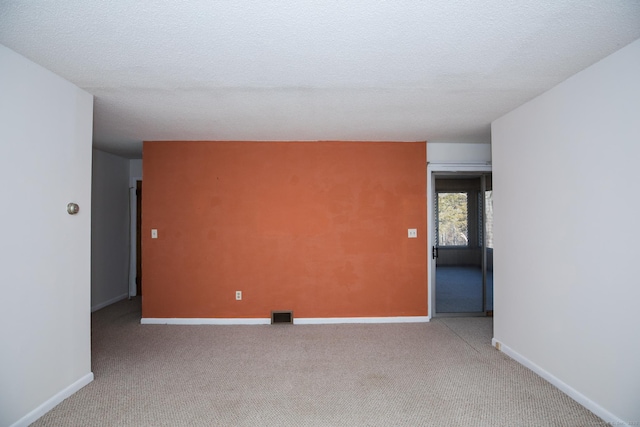 carpeted spare room with baseboards, visible vents, and a textured ceiling