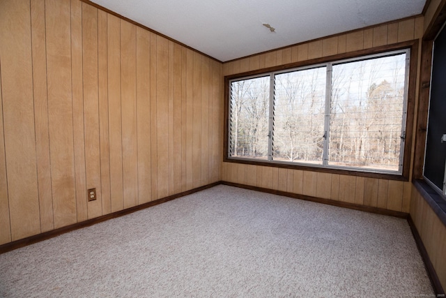 spare room with light carpet, wood walls, and ornamental molding