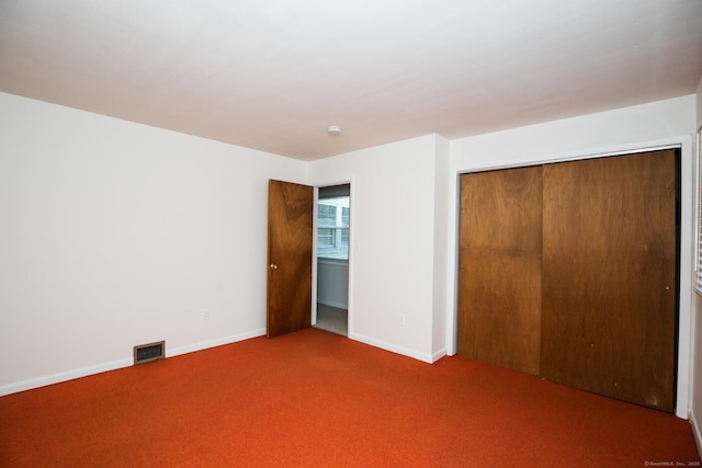 unfurnished bedroom featuring carpet, visible vents, a closet, and baseboards