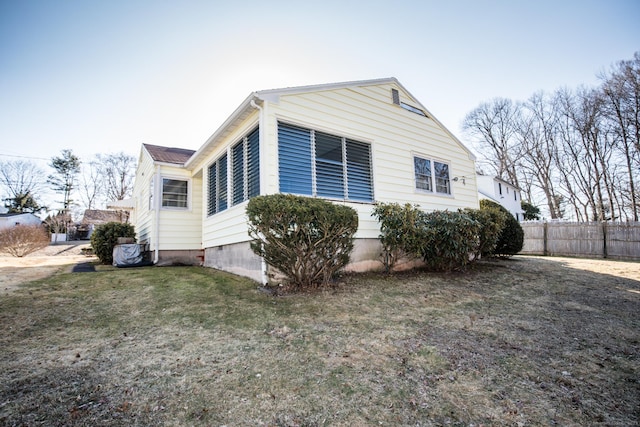 view of side of home with a yard and fence