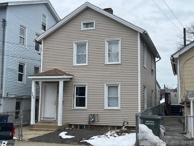 view of front of house with entry steps, a chimney, and fence