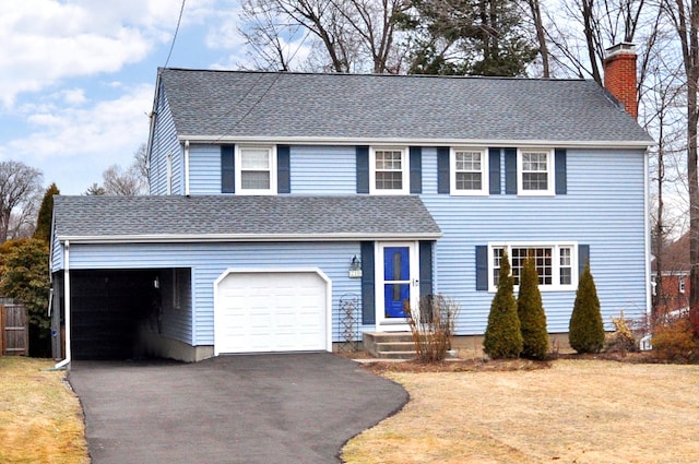 view of front of house featuring driveway, a chimney, and roof with shingles