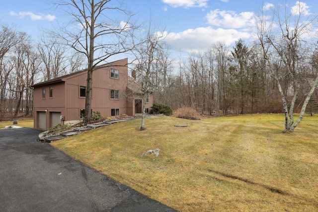 view of home's exterior featuring aphalt driveway, a yard, and an attached garage