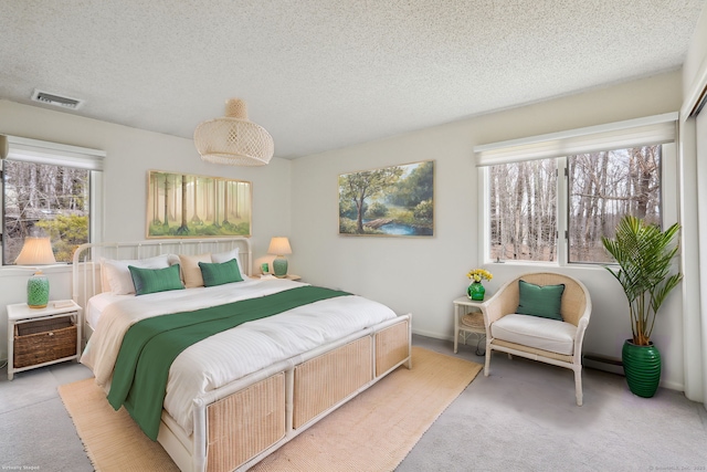 bedroom featuring light carpet, a textured ceiling, and visible vents