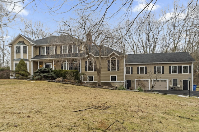 view of front of home with an attached garage, aphalt driveway, and a front yard