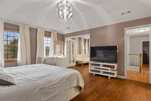 bedroom featuring visible vents, a notable chandelier, baseboards, and wood finished floors