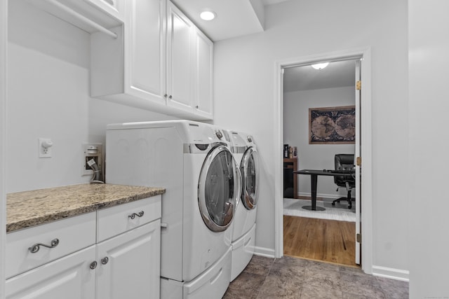 laundry area featuring washing machine and dryer, cabinet space, and baseboards