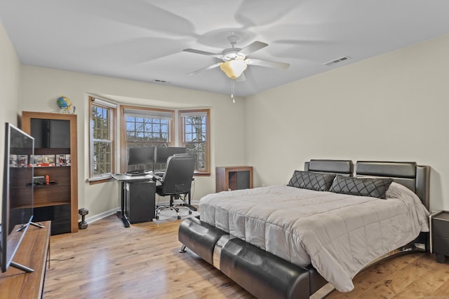 bedroom featuring light wood finished floors, baseboards, visible vents, and ceiling fan