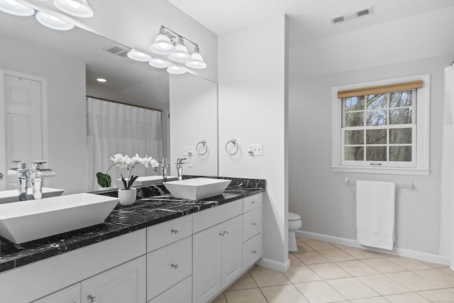 bathroom featuring toilet, visible vents, a sink, and tile patterned floors