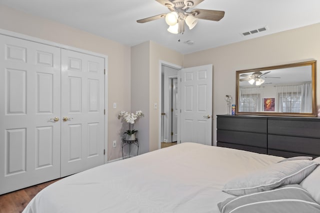 bedroom featuring ceiling fan, a closet, visible vents, and dark wood-style flooring