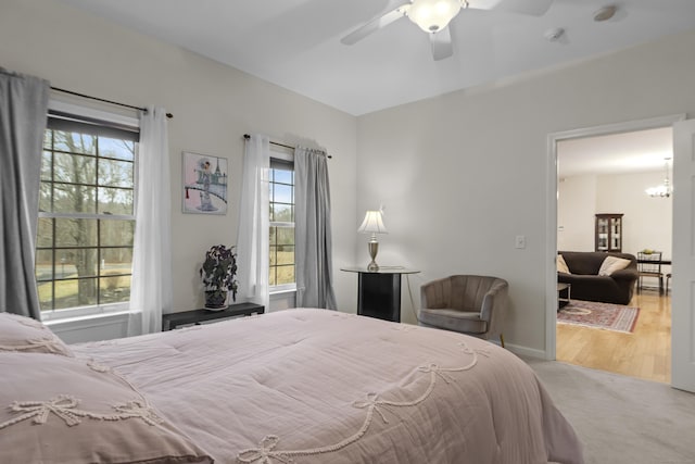 bedroom featuring carpet floors, multiple windows, and ceiling fan with notable chandelier