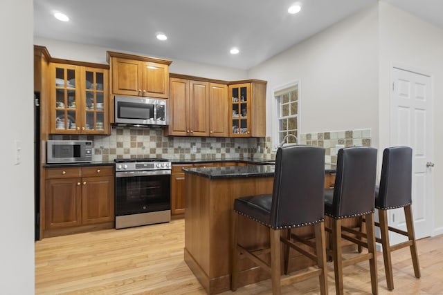 kitchen featuring brown cabinets, light wood finished floors, a breakfast bar area, and stainless steel appliances