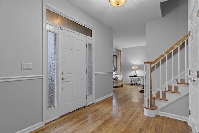 foyer entrance with stairs, wood finished floors, and baseboards