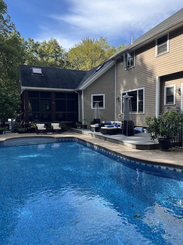 pool featuring a sunroom and a wooden deck