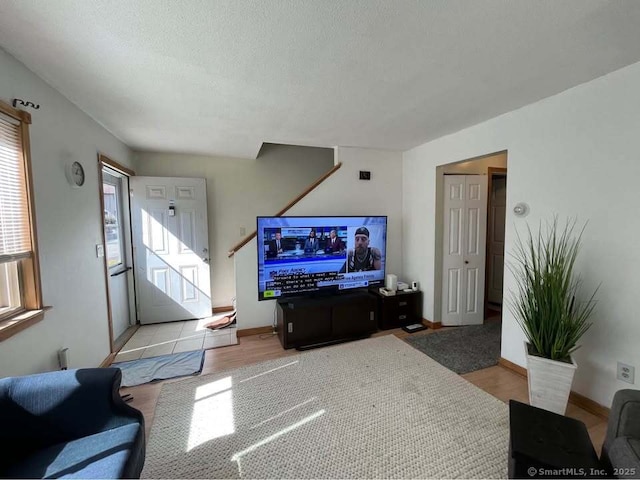 living area featuring wood finished floors, baseboards, and a textured ceiling