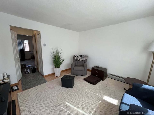 living area featuring a baseboard radiator, baseboards, and wood finished floors