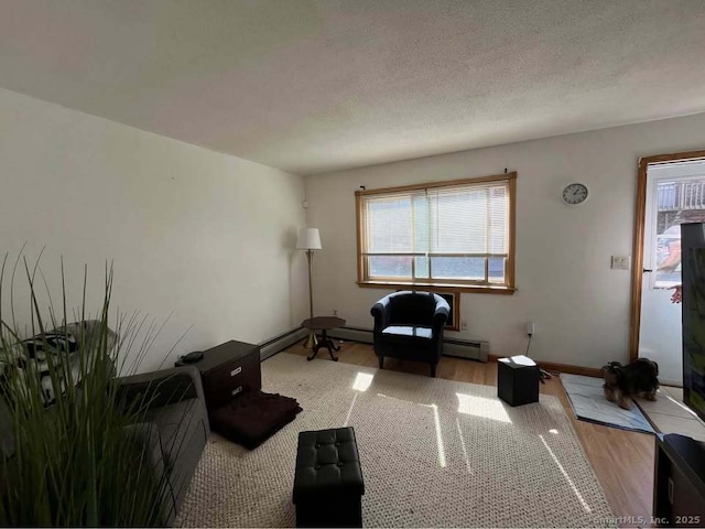 living area with baseboards, a textured ceiling, and wood finished floors