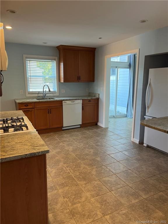 kitchen featuring light countertops, recessed lighting, white appliances, baseboards, and a sink