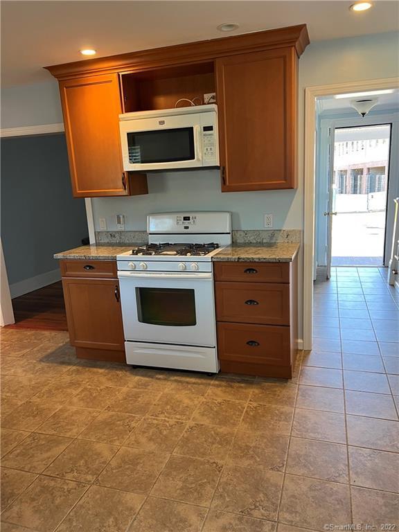 kitchen with brown cabinets, recessed lighting, baseboards, and white appliances
