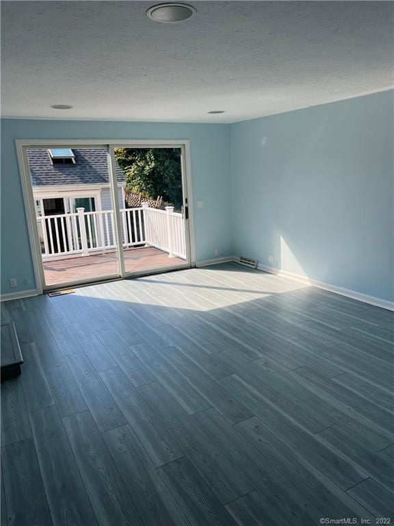 empty room with a textured ceiling, baseboards, and wood finished floors