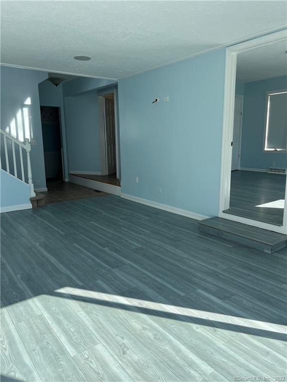 unfurnished room with stairs, wood finished floors, and baseboards
