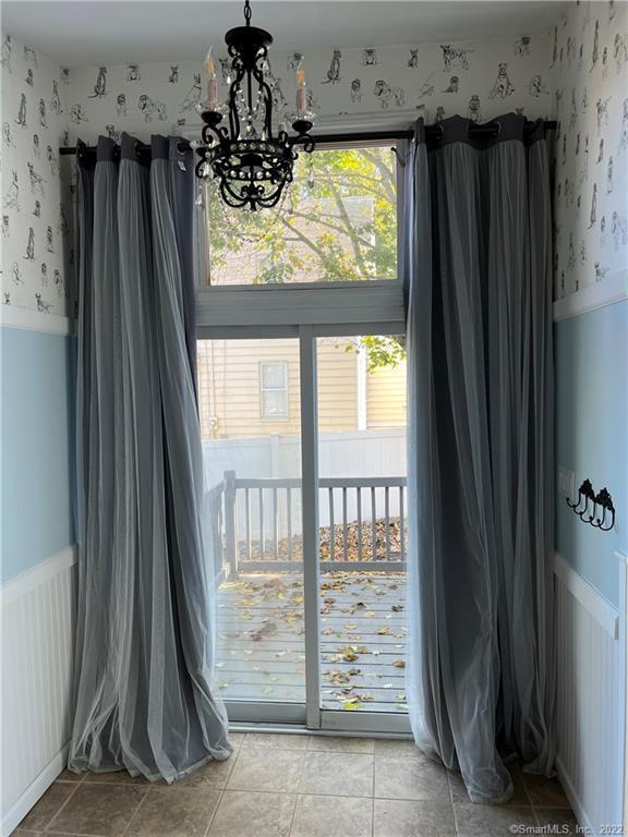 interior space with light tile patterned floors, a notable chandelier, wallpapered walls, and wainscoting
