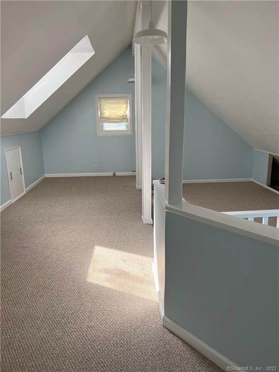 additional living space with baseboards, carpet flooring, and vaulted ceiling with skylight