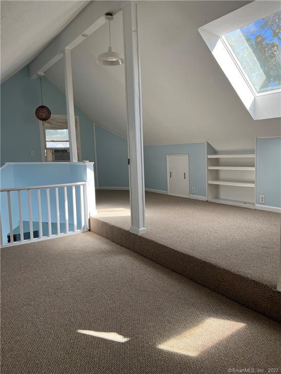 additional living space featuring carpet flooring, baseboards, and vaulted ceiling with skylight