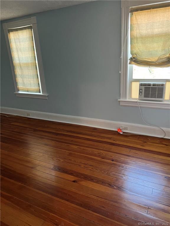spare room featuring baseboards, cooling unit, and hardwood / wood-style floors