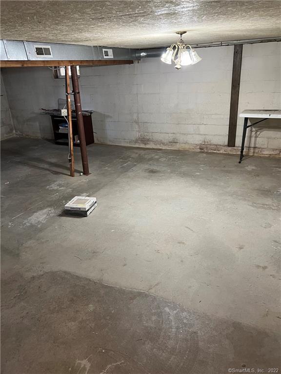 unfinished basement featuring concrete block wall and visible vents