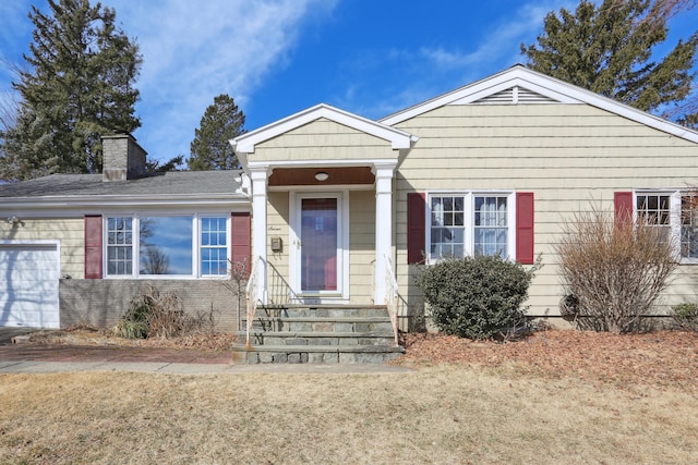 view of front of house with a garage, brick siding, and a chimney