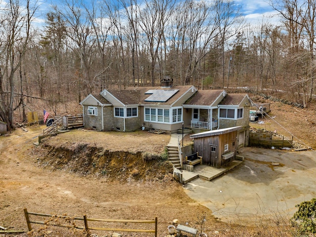 view of front of house featuring driveway, stairway, and solar panels