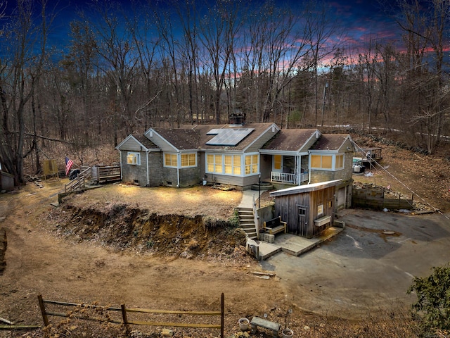 view of front facade featuring an attached garage, solar panels, fence, stairs, and driveway