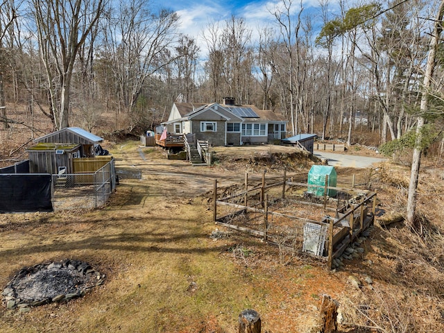 view of yard featuring a deck, dirt driveway, a vegetable garden, and fence