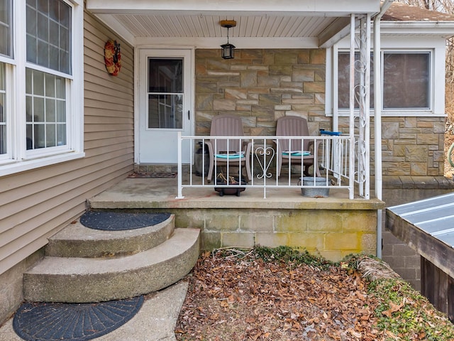 view of exterior entry featuring covered porch and stone siding