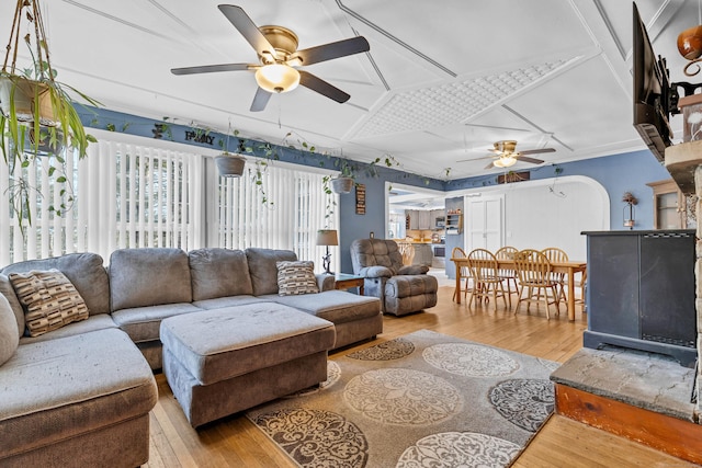 living room featuring a ceiling fan, arched walkways, and wood-type flooring