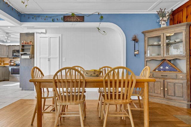 dining area with arched walkways, light tile patterned floors, visible vents, a ceiling fan, and ornamental molding