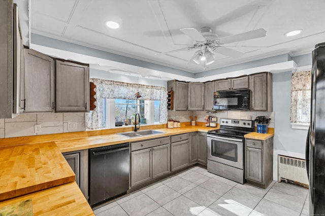 kitchen featuring radiator heating unit, wood counters, a sink, black appliances, and backsplash