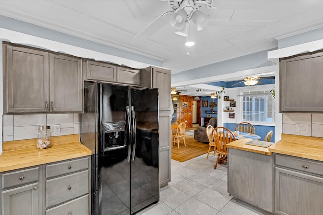 kitchen featuring light tile patterned floors, butcher block countertops, a ceiling fan, backsplash, and black refrigerator with ice dispenser