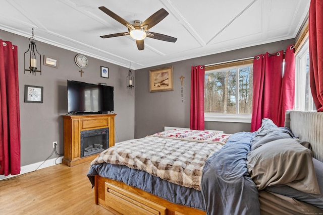 bedroom featuring ceiling fan, multiple windows, a fireplace, and light wood-style floors