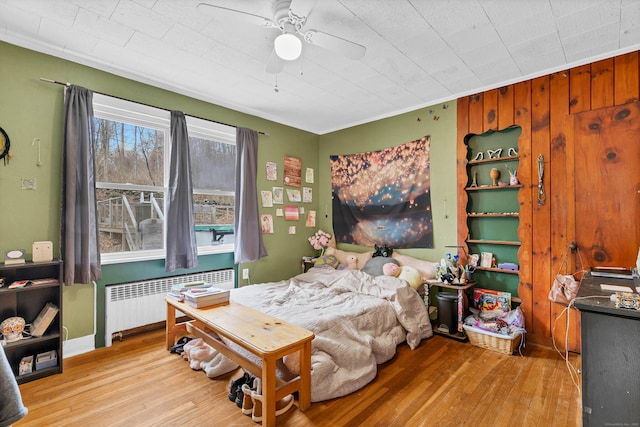 bedroom featuring light wood-style floors, a ceiling fan, and radiator