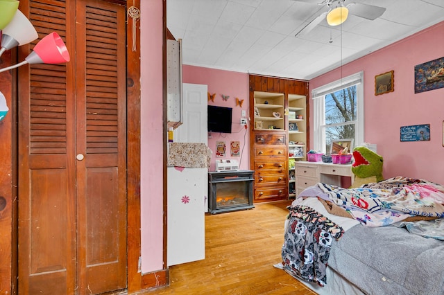 bedroom with a fireplace, wood finished floors, and a ceiling fan