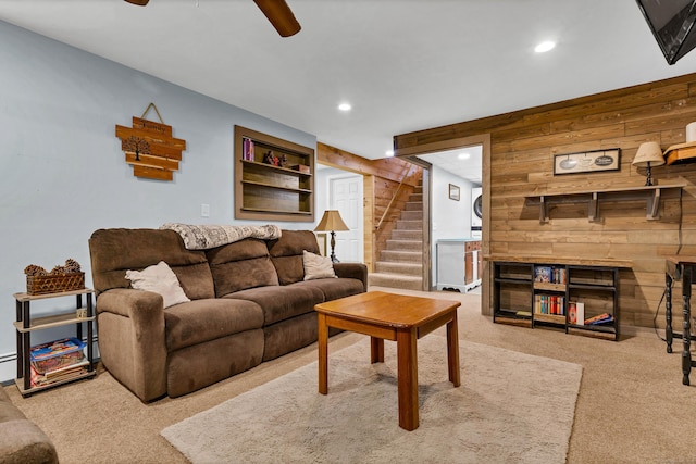 living area featuring carpet, a fireplace, recessed lighting, stairway, and wooden walls