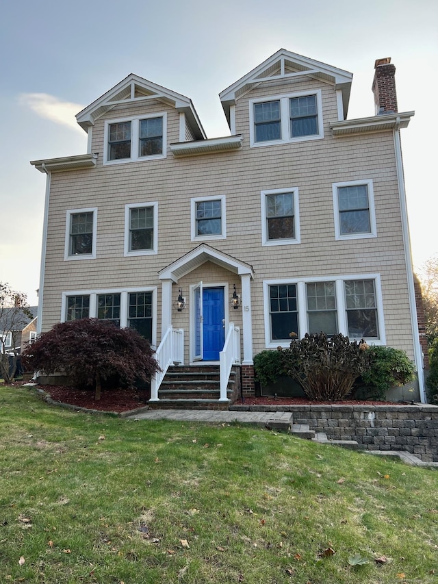 view of front of home with a chimney and a front lawn