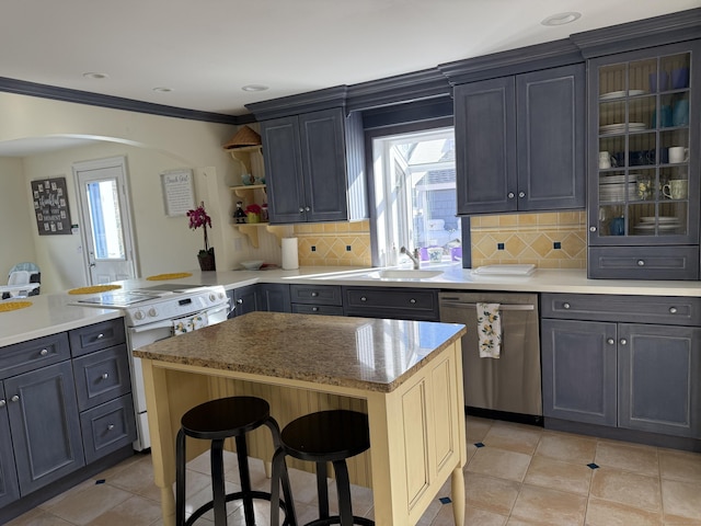 kitchen featuring a breakfast bar area, a sink, stainless steel dishwasher, white range with electric stovetop, and decorative backsplash