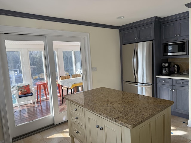 kitchen featuring light tile patterned floors, tasteful backsplash, appliances with stainless steel finishes, a center island, and light stone countertops