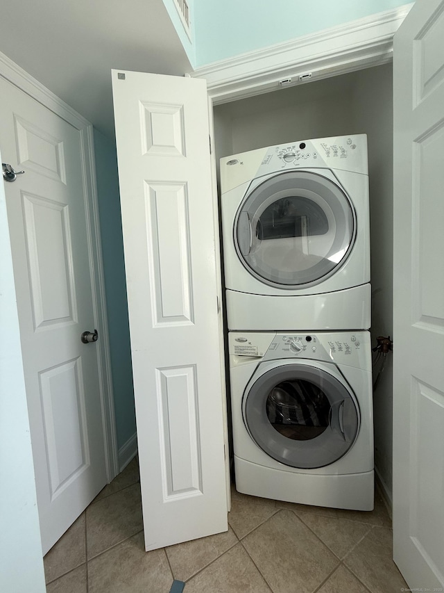 washroom featuring light tile patterned floors, laundry area, stacked washing maching and dryer, and visible vents